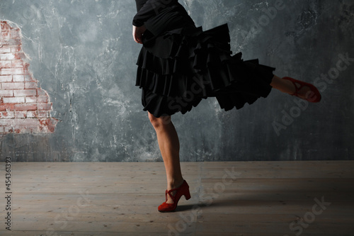 Young adult spanish woman dancing flamenco on gray vintage studio background