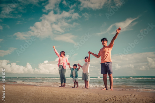 Happy family on the beach against blue sea and sky background at sunset. Holiday and summer travel concept