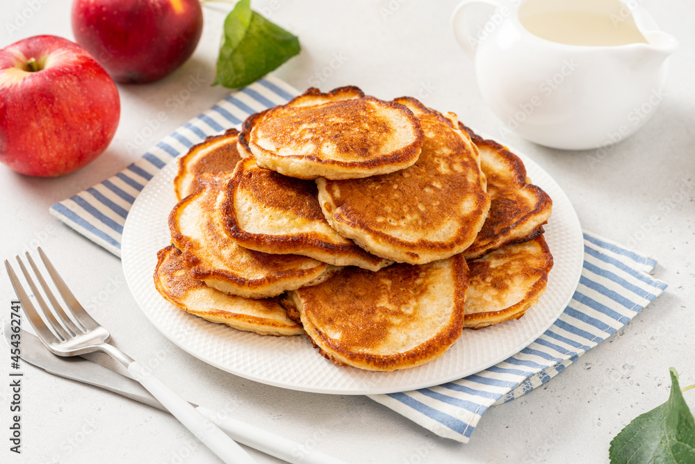 Homemade apple pancakes in a white plate on a gray concrete background. Tasty breakfast
