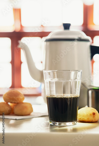 Copo de café com bule e pães ao fundo photo