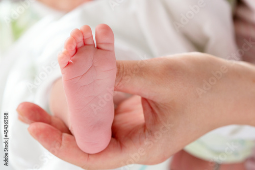 Foot of a newborn baby in a female hand. Massage the feet of a newborn