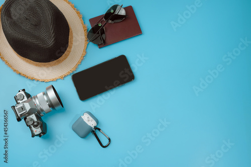flat lay travel accessory in new normal with phone camera and passport on blue background