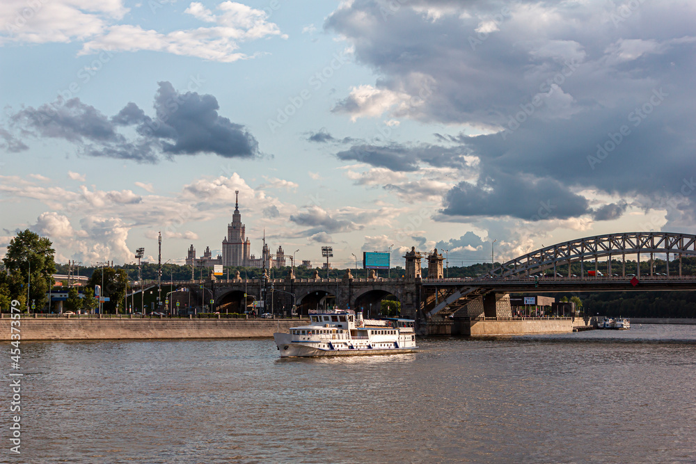 River cruise ship sails along the Moscow river against the background of an old bridge