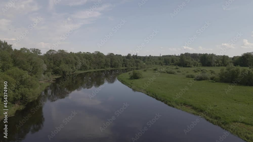 Static scene of a calm river flowing through meadows and forests in summer day Static scene of a calm river flowing through meadows and forests in summer day