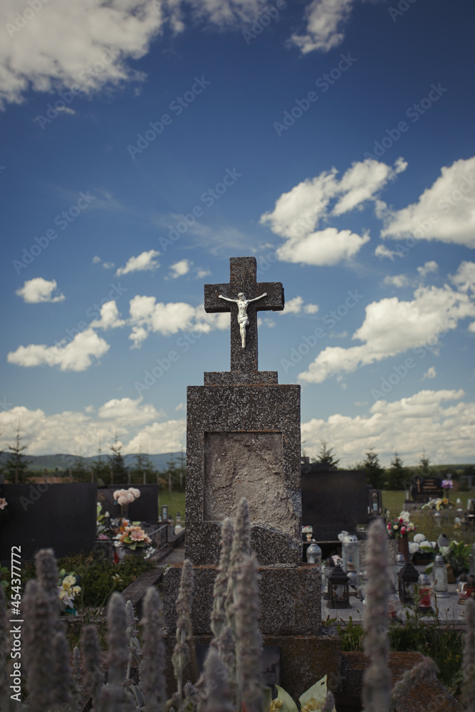 Aged cross tomb stone at cemetery with cloudy sky. Old tombstone in a graveyard Aged cross tomb stone at cemetery with cloudy sky. Old tombstone in a graveyard