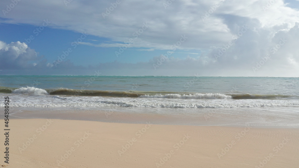 Colorful Aerial View of tropical beach with turquoise blue ocean water and waves lapping on hidden white sand beach. Blue skies with green trees vegetation. Waimanalo Beach, Oahu Hawaii Island. 4k.