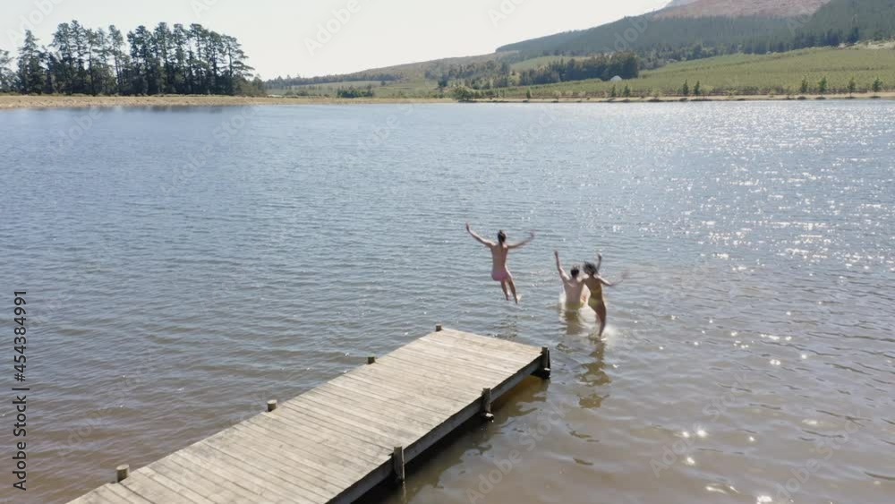 aerial view happy friends jumping off jetty in lake having fun splashing in water enjoying freedom on summer vacation overhead drone aerial view happy friends jumping off jetty in lake having fun splashing in water enjoying freedom on summer vacation overhead drone