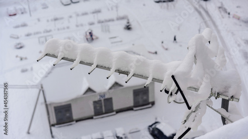 Long metal tv antenna covered with snowdrift hanging on city house