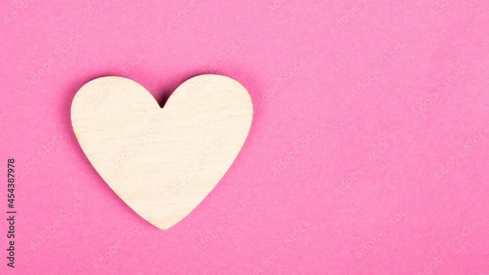 valentine wooden heart on pink background with copy space.