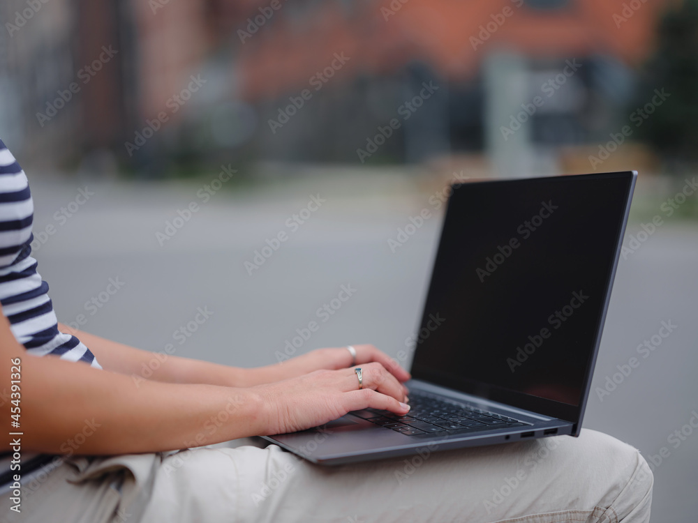 Young asian female student working at laptop sit down on bench outside on urban city street. Happy lady distance learning, education and online shopping. hands closeup Young asian female student working at laptop sit down on bench outside on urban city street. Happy lady distance learning, education and online shopping. hands closeup