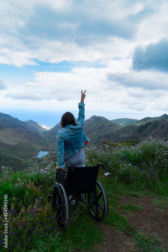 Disabled handicapped woman in wheelchair on mountain hill enjoying view