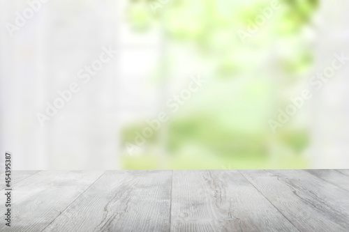 Empty rustic wooden bright table top in front of abstract blurred curtain window natural green background. Template for your product display montage. Space for design.