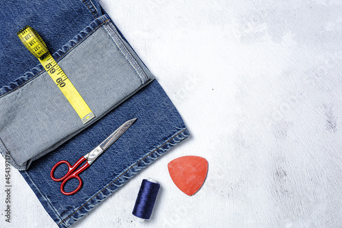 Obraz na plátně Handicraft, clothing repair. Ripped blue jeans sewing accessories