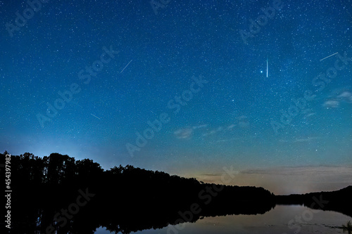Deszcz meteorytów podczas maksimum Perseidów. Rój spadających gwiazd w nocy. Najbardziej spektakularne meteory nad jeziorem.