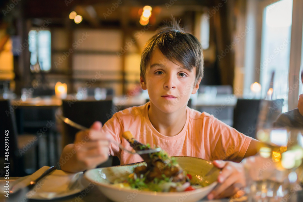 Preteen child, cute boy, eating lamb in a restaurant, cozy atmosphere, local small restaurant in Tromso, Norway