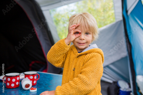 Cute little toddler boy, eating vitamins on a family holiday to improove his health and for better imunity while traveling and sleeping in a tent photo