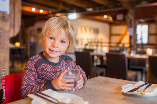 Preschool child  cute boy  drinking water in a restaurant  cozy atmosphere  local small restaurant in Tromso  Norway