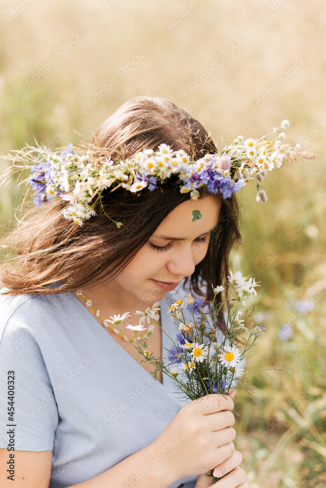 Naklejka premium Cute smiling little girl with flower wreath on the meadow. Portrait of adorable small kid outdoors.