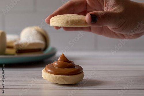 woman with two cookies putting together a alfajor