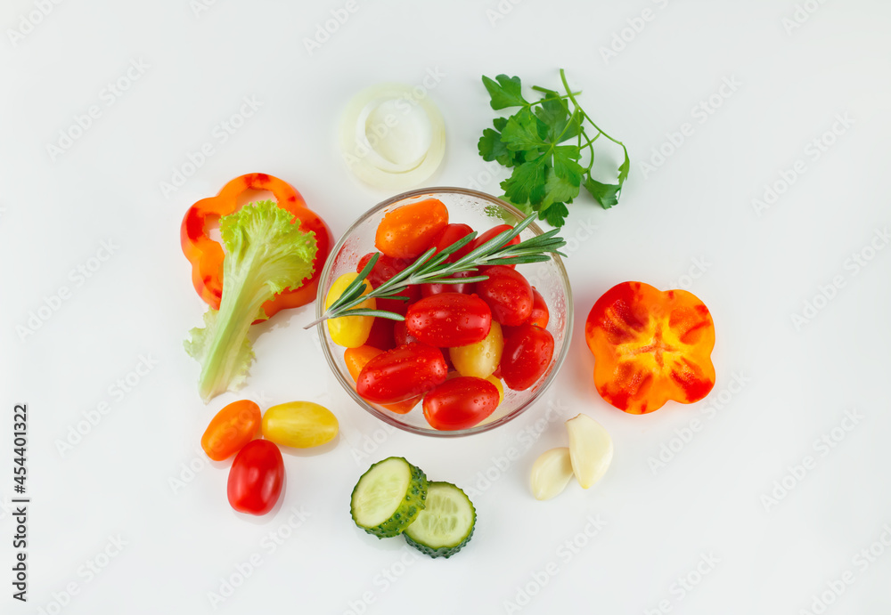 In the center - cherry tomatoes in a salad bowl, around chopped vegetables, lettuce, peppers, cucumbers, onions. top view, on white background In the center - cherry tomatoes in a salad bowl, around chopped vegetables, lettuce, peppers, cucumbers, onions. top view, on white background