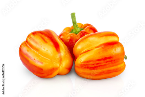 Three striped red-yellow sweet peppers on a white background. Isolated, with shadow