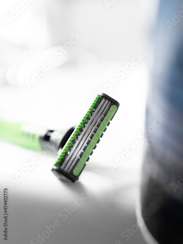 Shaving razor blade close-up, selective focus. Bathroom product still life with green and soft blue colors contrasted against the bright white backdrop.