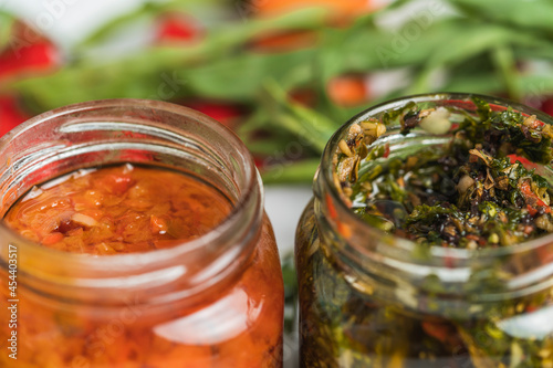 Selective focus on two jars with Rocoto and Chimichurri sauces. photo