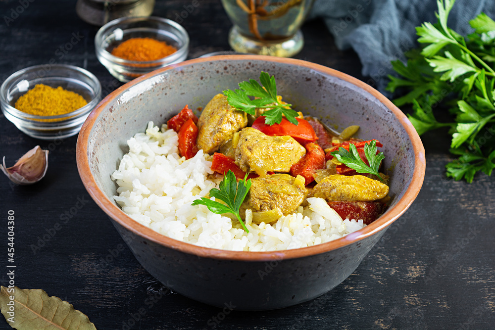 Spicy chicken curry with rice. Curry sauce with chicken and rice on dark background Spicy chicken curry with rice. Curry sauce with chicken and rice on dark background
