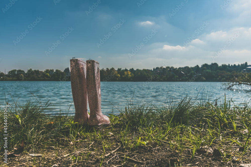 boots of child standing by the pond in the sunset time boots of child standing by the pond in the sunset time