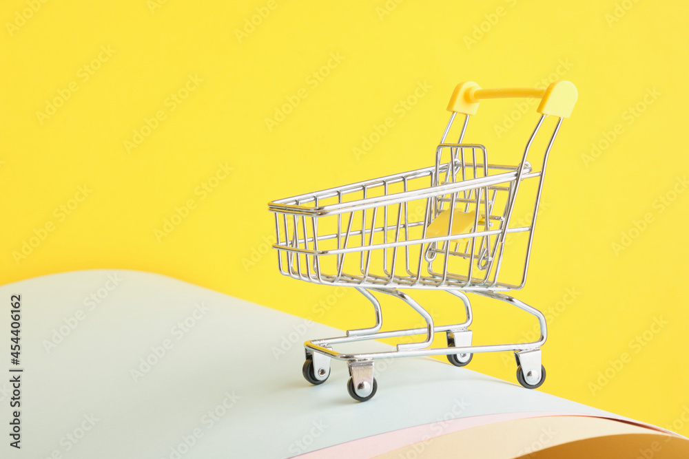 Small shopping market trolley on a yellow background, copy space, shopping concept