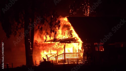 2021 - A house is engulfed in flames at night during the disastrous Dixie Fire in Northern California. photo