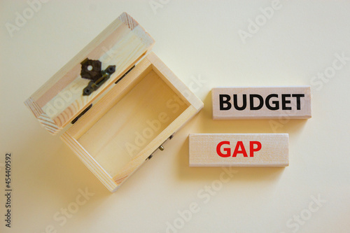 Budget gap symbol. Concept words 'budget gap' on wooden blocks on a beautiful white background, empthy wooden chest. Business and budget gap concept, copy space. photo