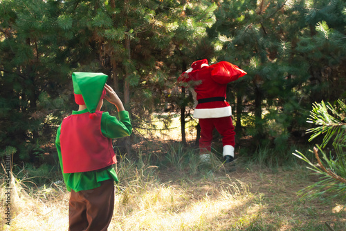 Cute boy elf declassified Santa Claus with a bag of gifts in the woods among the Christmas trees, Santa found, the end of the holiday Christmas and New Year photo