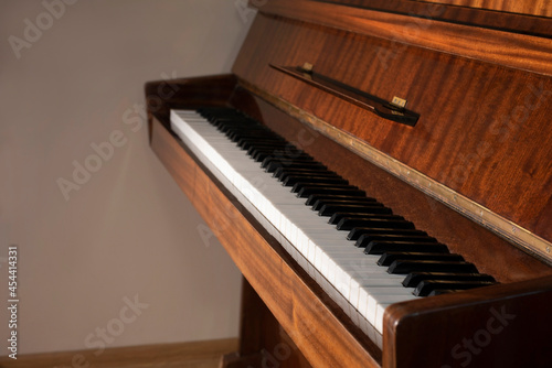 Part of a classical wooden piano, the concept of playing the piano, music education. Focus on the keys
