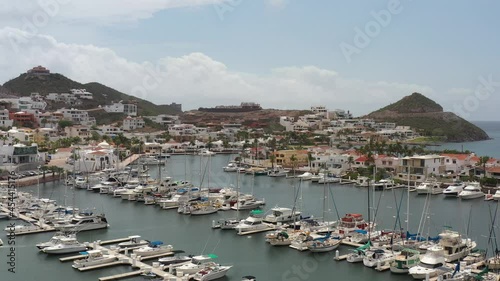 Aerial view of Marina Real in San Carlos, Sonora. Drone flying forward over the yachts and boats with a blue sky as background.