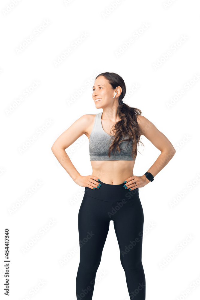 Young woman is standing in superhero posture. She is wearing sportswear over white background. Young woman is standing in superhero posture. She is wearing sportswear over white background.