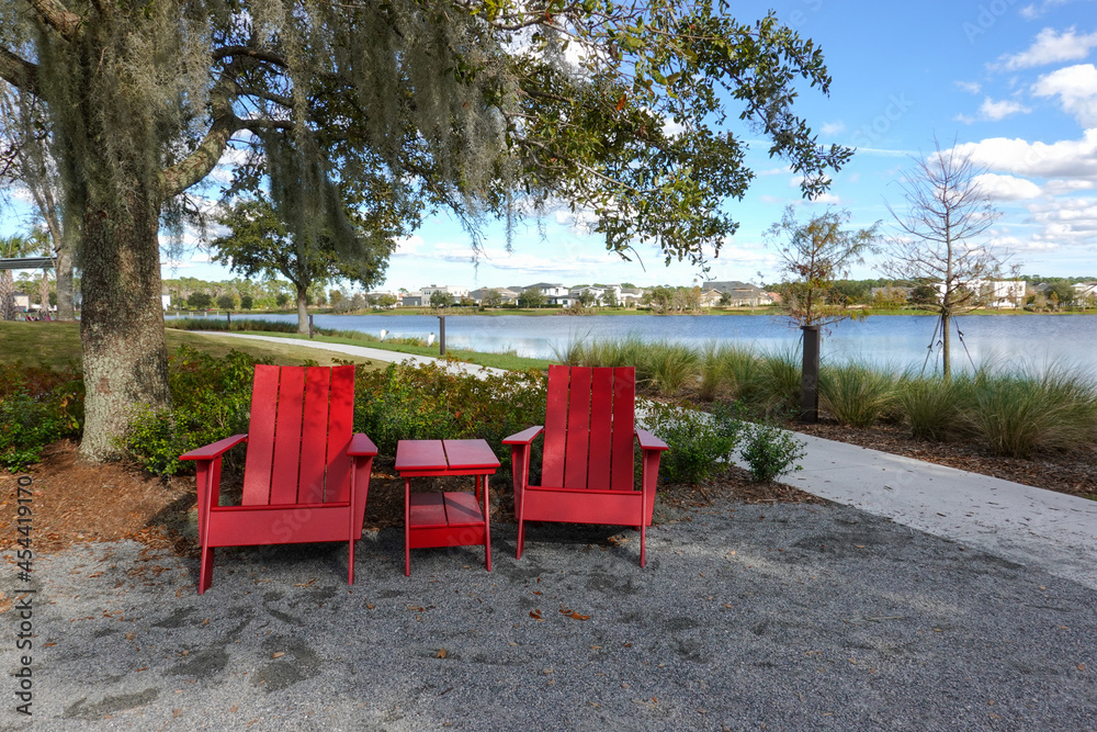 Two chairs sitting in a park by a lake in Laurete Park in Lake Nona, Orlando, FL on a beautiful sunny day.