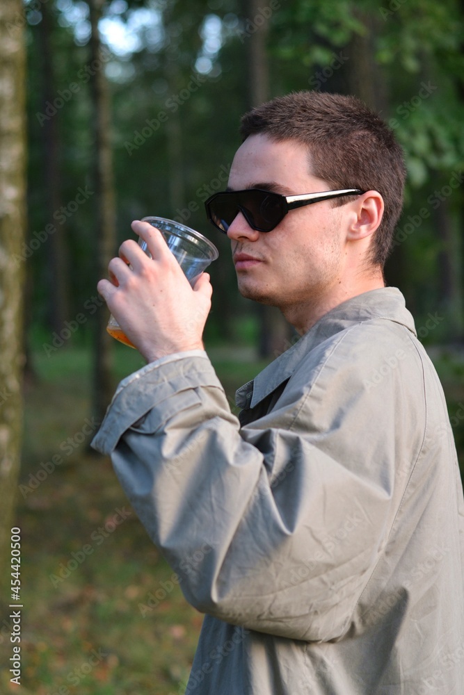 The brunette guy is posing in black glasses and a gray cloak. The brunette guy is posing in black glasses and a gray cloak.