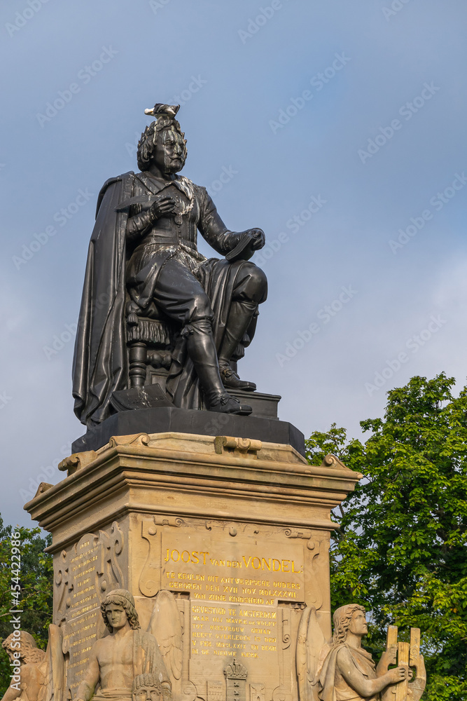 Obraz premium Amsterdam, Netherlands - August 14, 2021: Closeup of Vondel bronze statue on his beige sculpted pedestal under blue sky. Bird on his head.