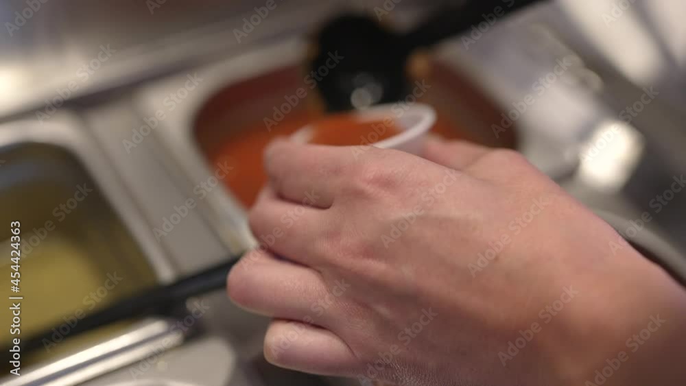 This close up video shows a point of view perspective of an anonymous hand ladling and pouring red salsa into a container at a Mexican restaurant's salsa bar. This close up video shows a point of view perspective of an anonymous hand ladling and pouring red salsa into a container at a Mexican restaurant's salsa bar.