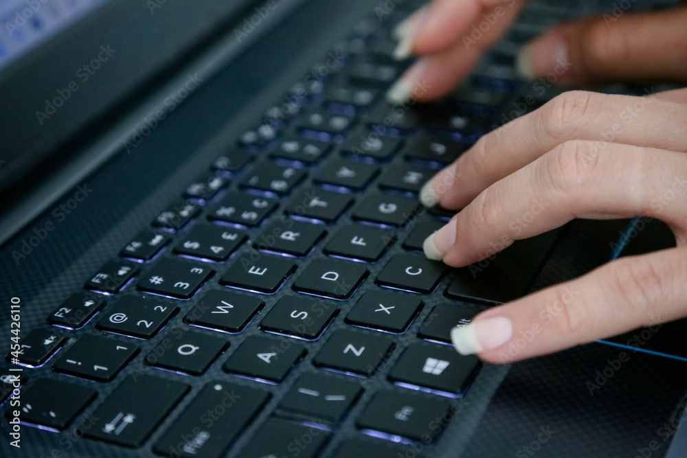 hand on the black keyboard of a computer typing text.
