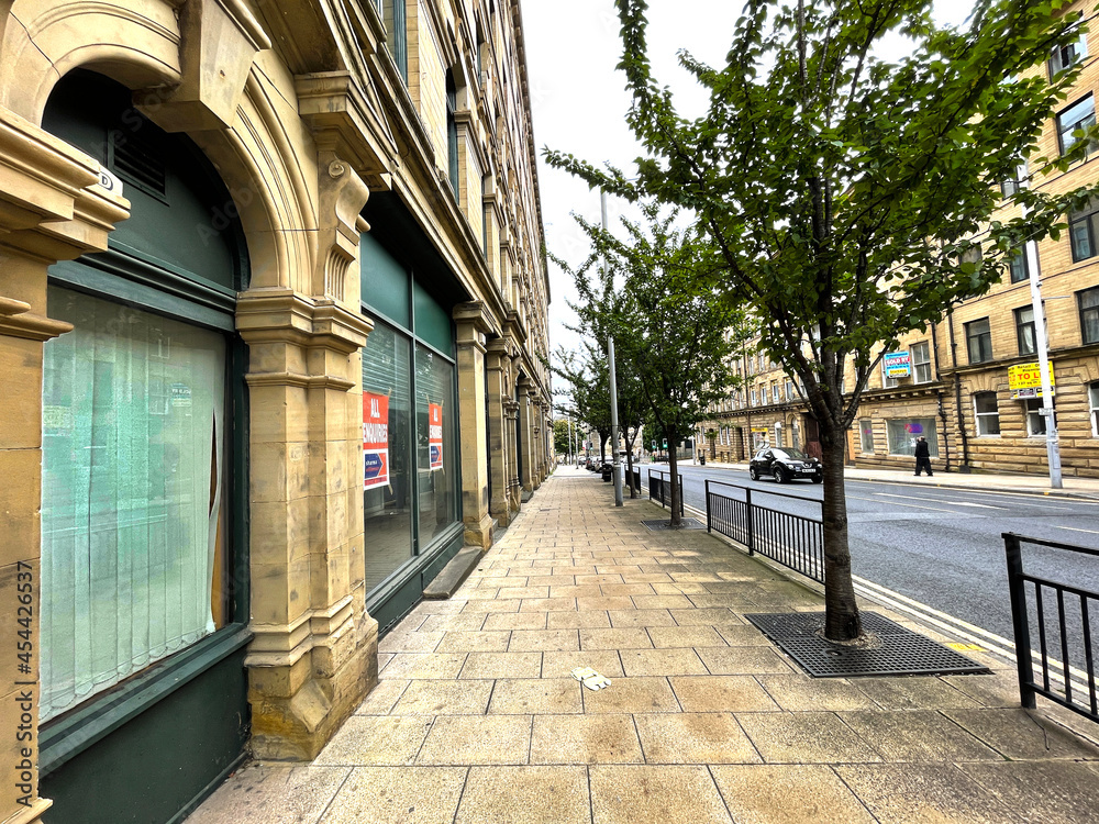 Obraz premium View along a tree lined pavement, with adjacent Victorian buildings on, Manor Row, Bradford, Yorkshire, UK