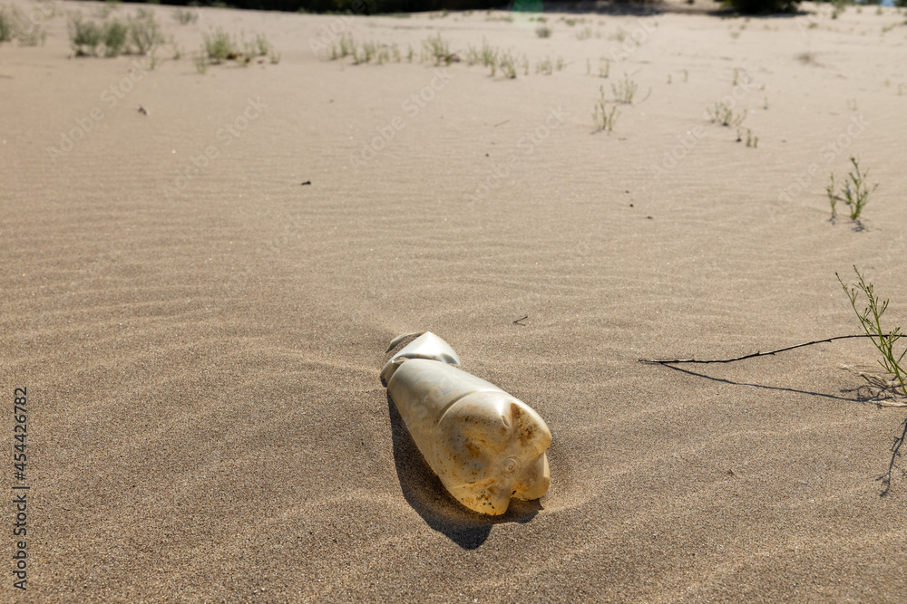 Obraz premium a dirty plastic bottle is lying on a sandy beach