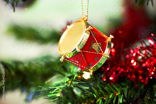 Christmas tree drum decoration hanging on branch with red tinsel closeup © Dib Dab Digital