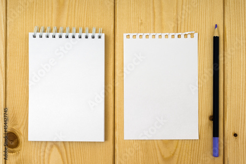 notepad with a torn off white sheet and a pencil on a wooden background
