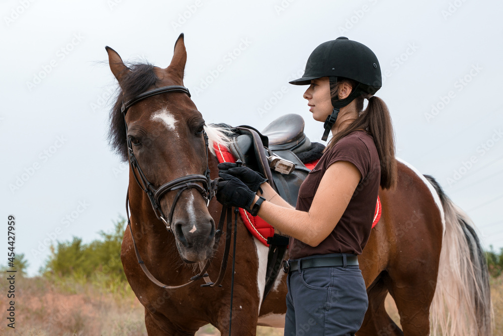 Obraz premium A girl in a field stands next to her skewbald horse
