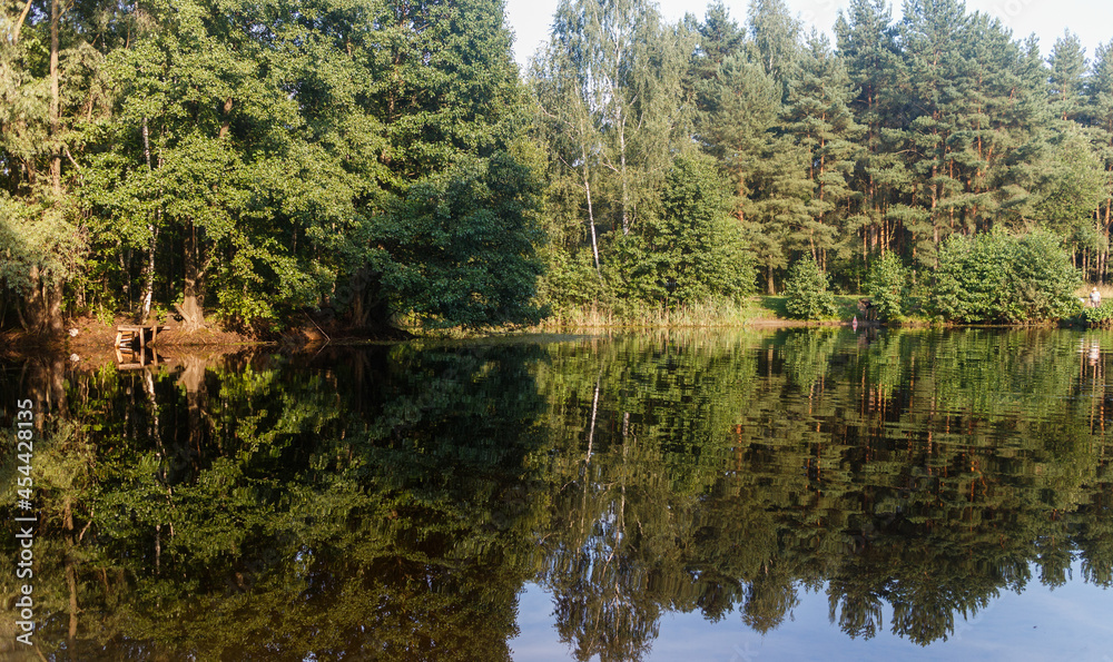 Moscow oblast, Russia. Summer day. Small lake shore. Reflections in water Moscow oblast, Russia. Summer day. Small lake shore. Reflections in water