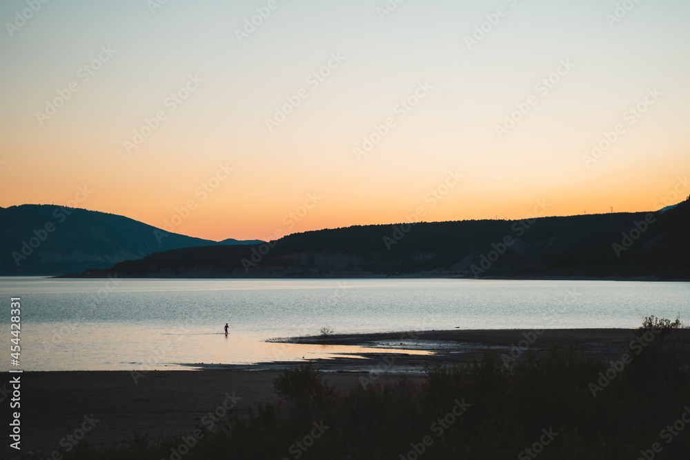 Man coming out of the water of a lake during sunset in Spain