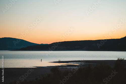 Man coming out of the water of a lake during sunset in Spain