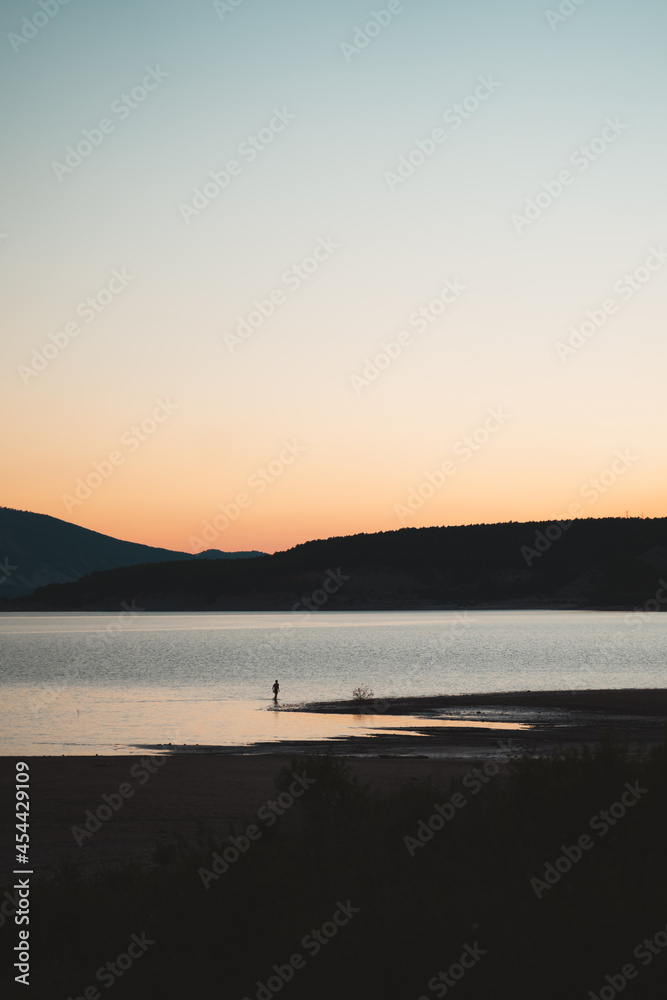 Man coming out of the water of a lake during sunset in Spain